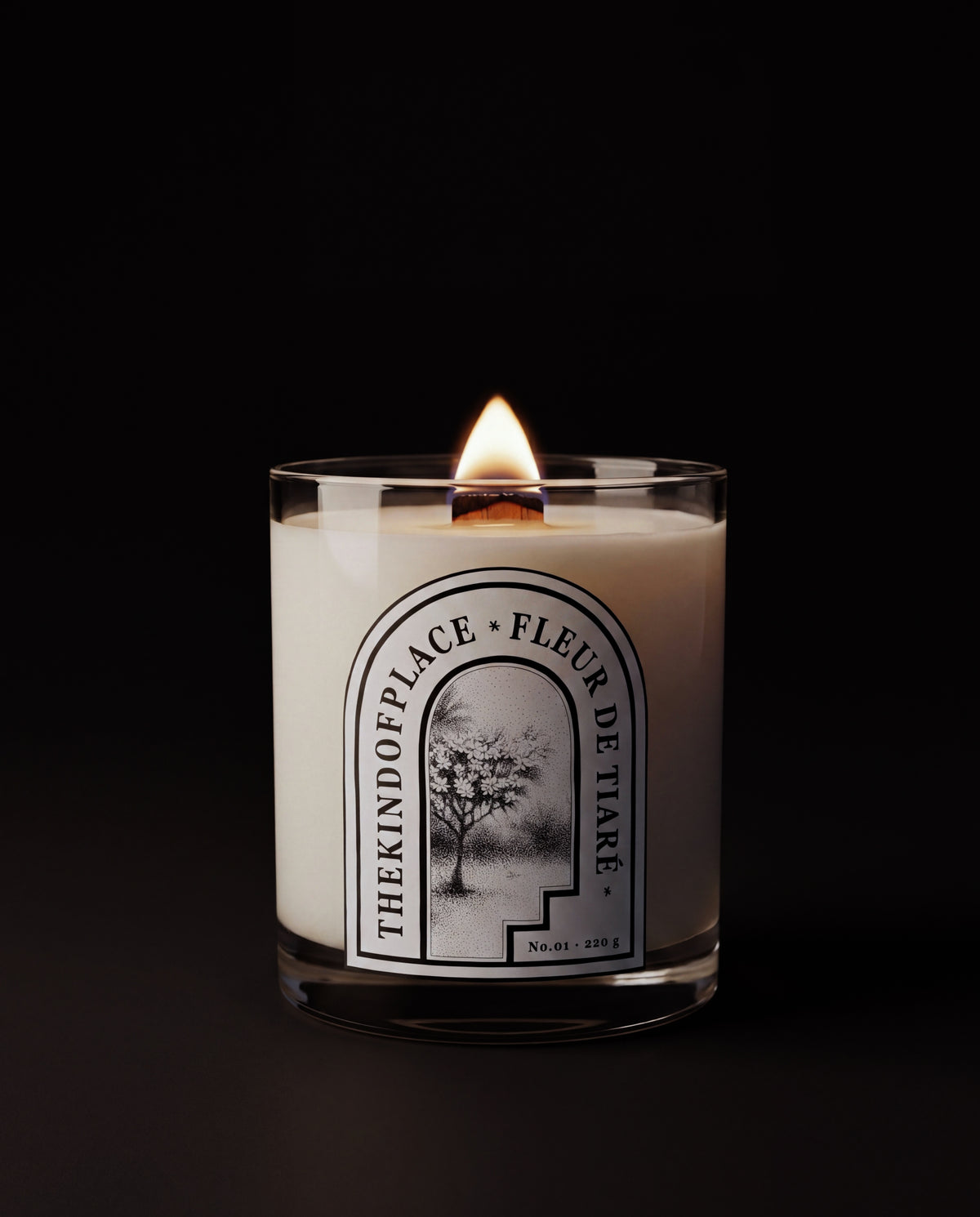 Fleur de Tiaré candle lit on a side table, the wood wick burning low, wax pool forming.