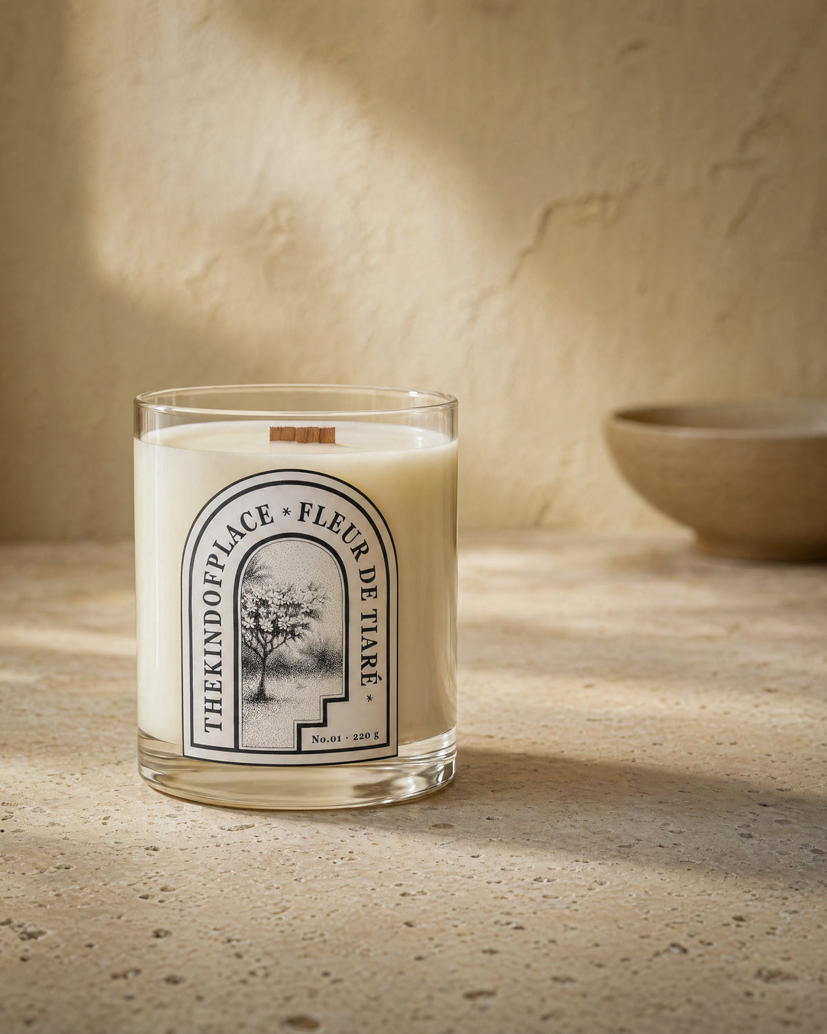 Fleur de Tiaré candle on a side table in soft afternoon light, beside everyday objects.